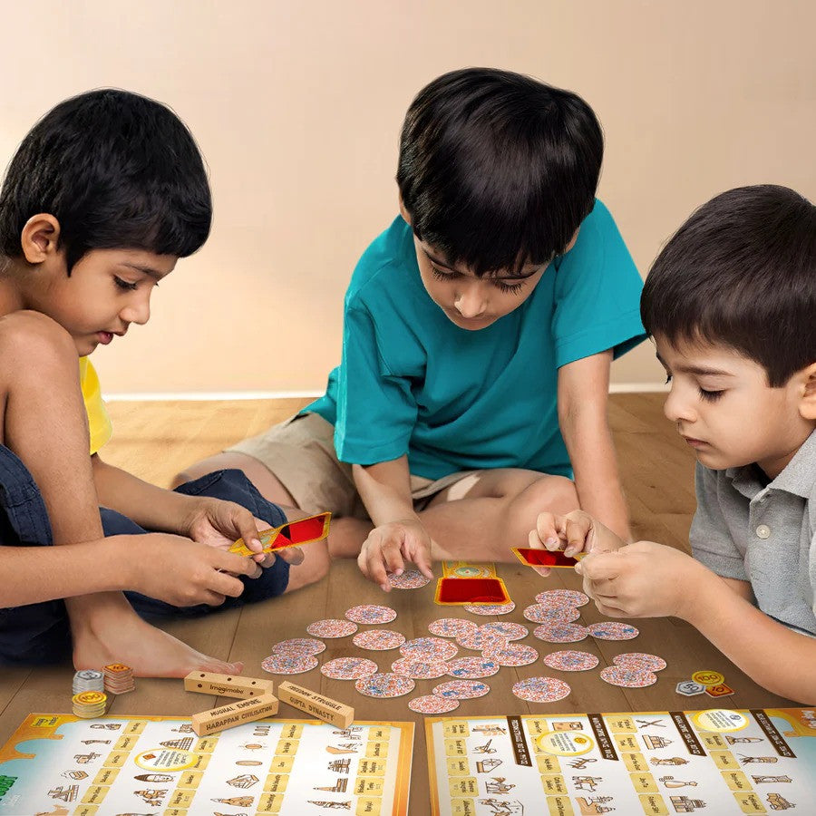 Three children playing with a board game on a wooden floor.