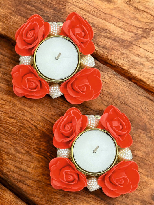 Decorative candle holders with red flowers and pearls on a wooden surface