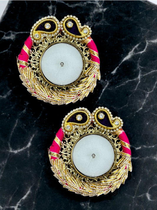 Pair of ornate earrings with gold, pink, and black design on a dark marble background