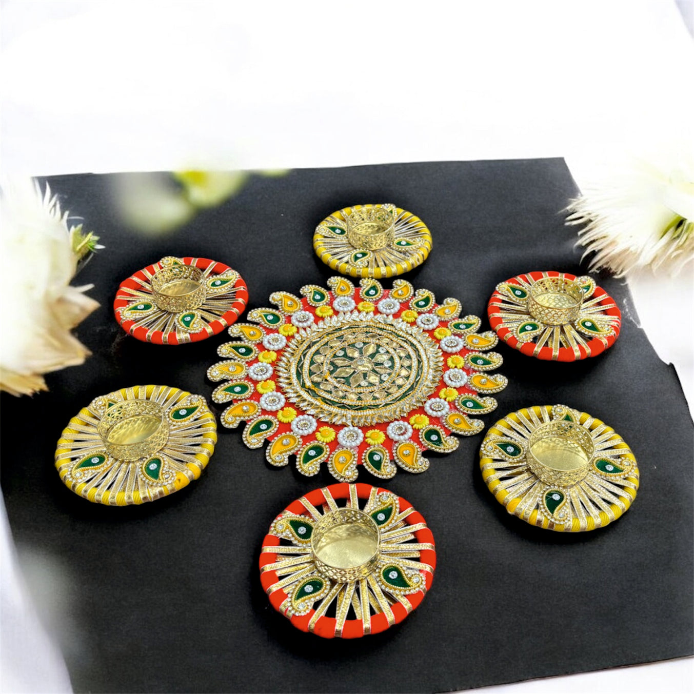 Decorative colorful pattas on a black surface with flowers in the background