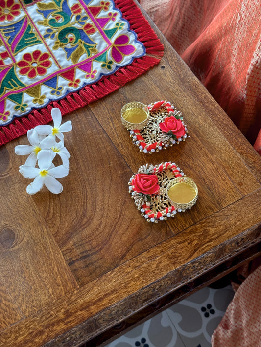 Decorative items including a colorful embroidered fabric, flowers, and ornate coasters on a wooden surface.