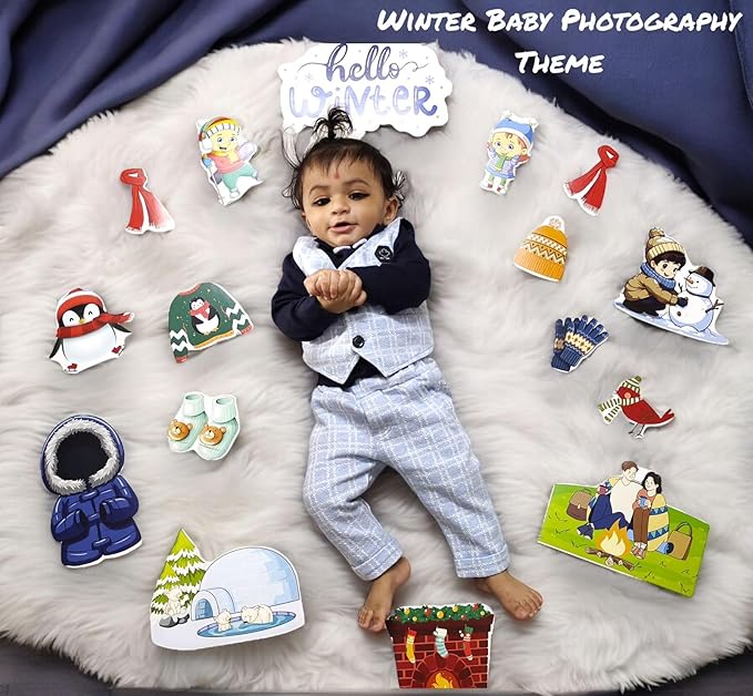 Baby in a winter-themed outfit surrounded by winter-themed props on a fluffy white surface.