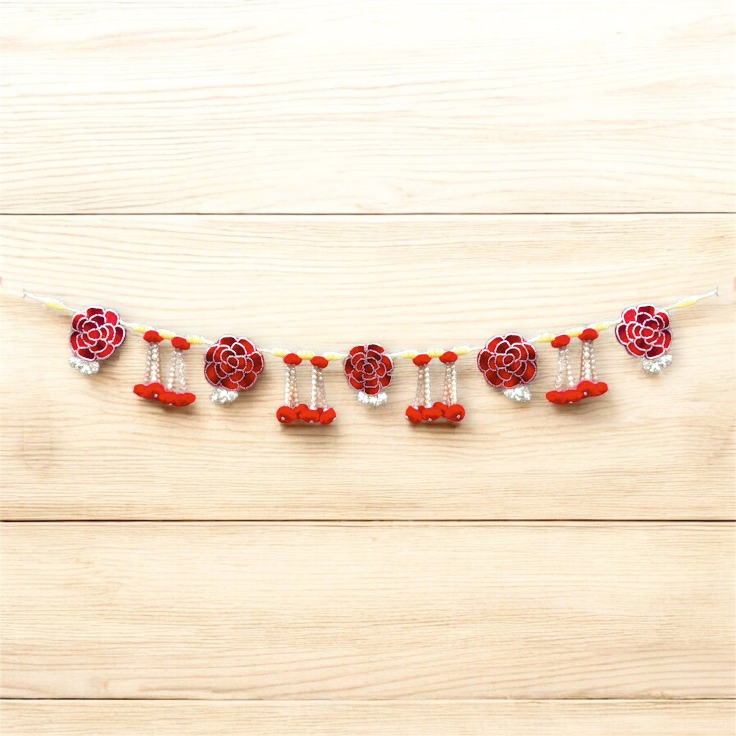 Decorative garland with red and white flowers on a wooden surface