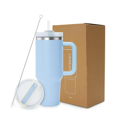 Light blue insulated mug with handle and straw lid next to a cardboard box on a white background