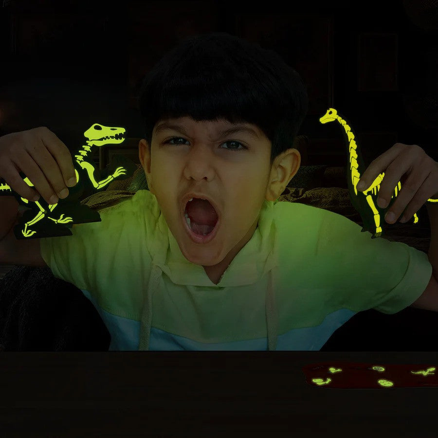 Child holding glow-in-the-dark dinosaur toys in a dark setting
