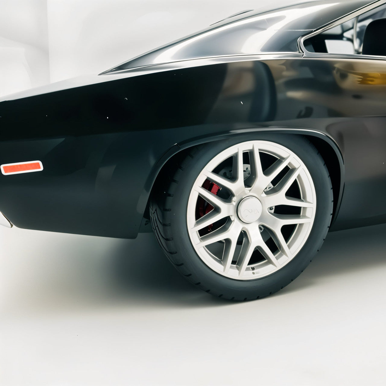 Close-up of a black car's wheel with a silver rim on a white background