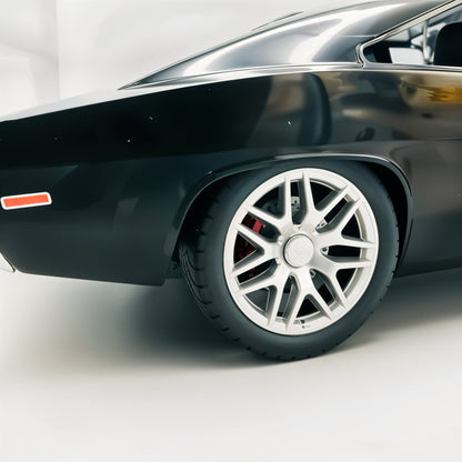 Close-up of a black car's wheel with a silver rim on a white background
