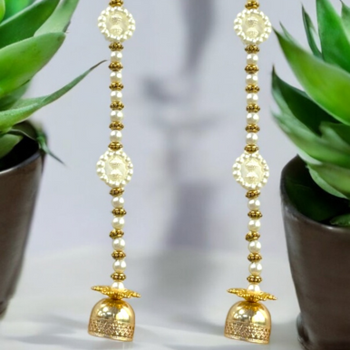 Pair of gold and pearl earrings with a blurred plant background