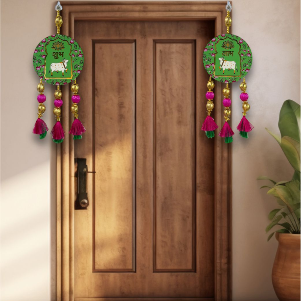 Decorative door hanging with green emblem and pink tassels on a wooden door.