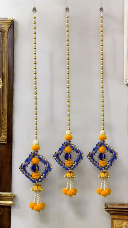 Decorative hanging elements with blue and yellow beads on a white wall.